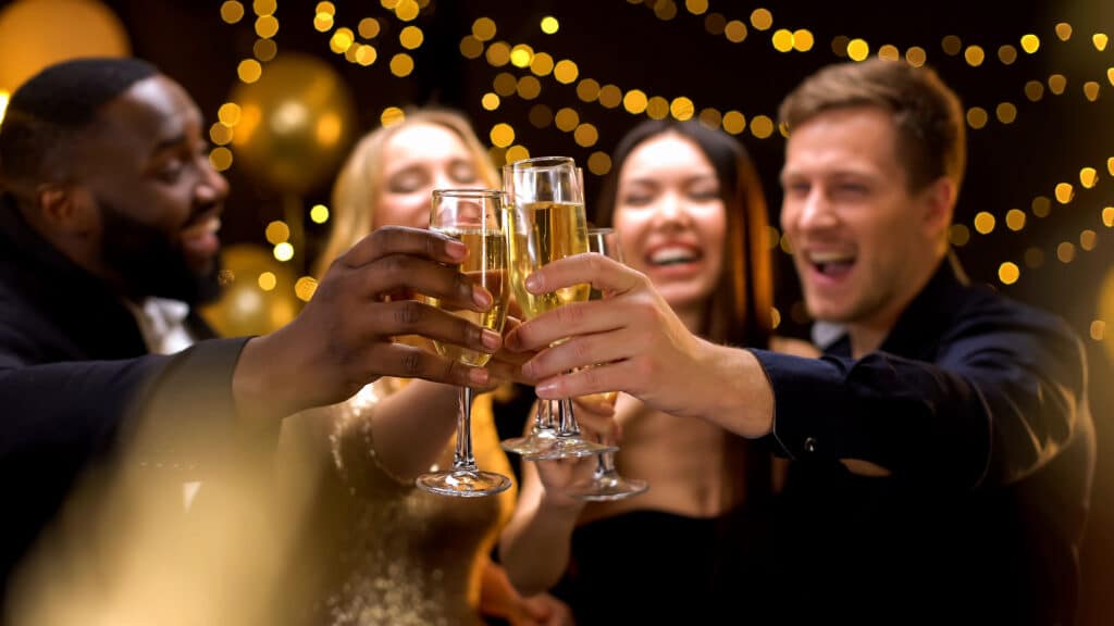 happy multi ethnic company clinking beverage glasses, celebrating new year