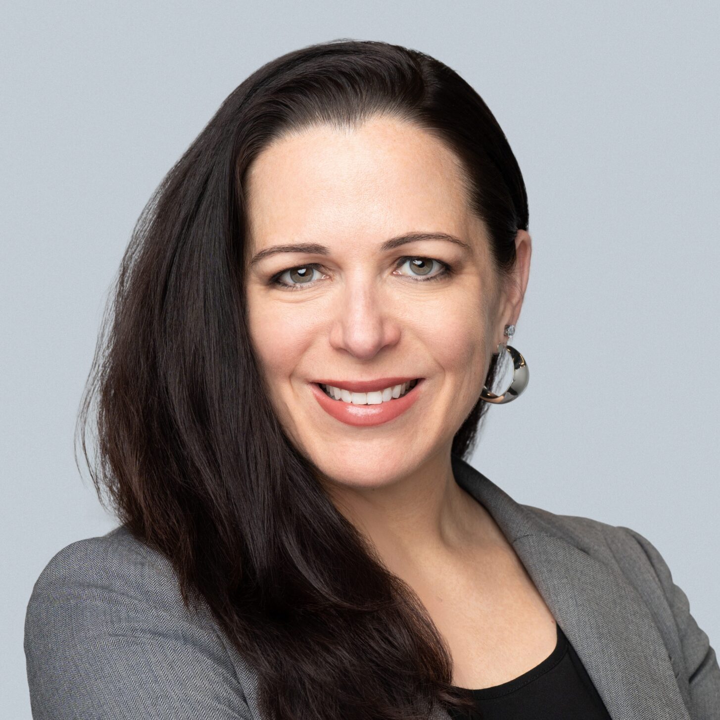 Woman in gray blazer smiling confidently.