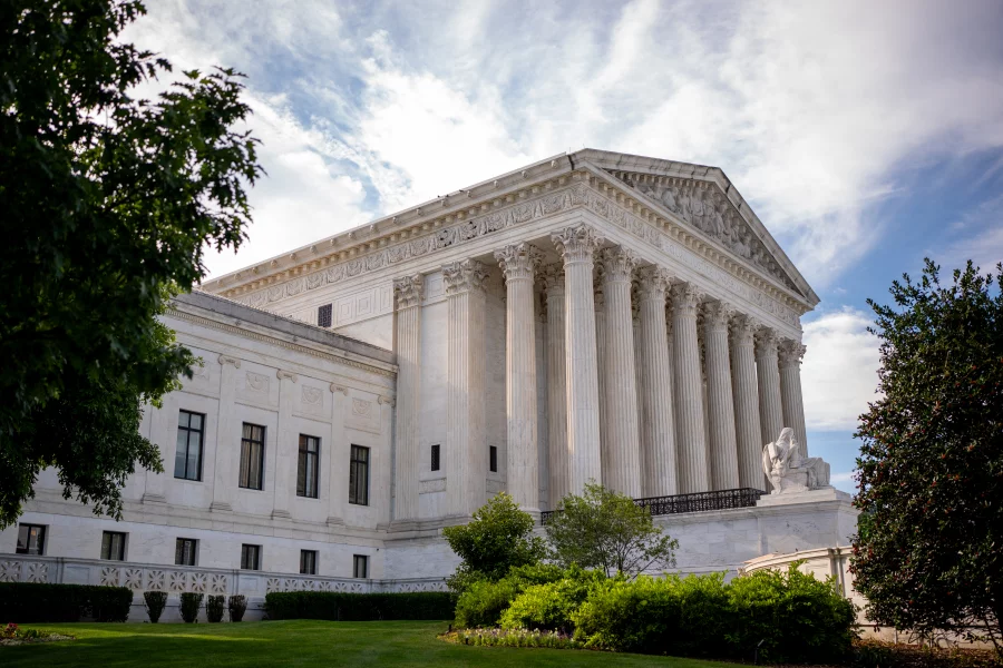Supreme Court building with columns under cloudy sky.