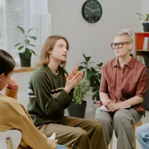 Support group meeting with three people discussing.