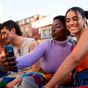 Friends taking a selfie outdoors during Pride event.