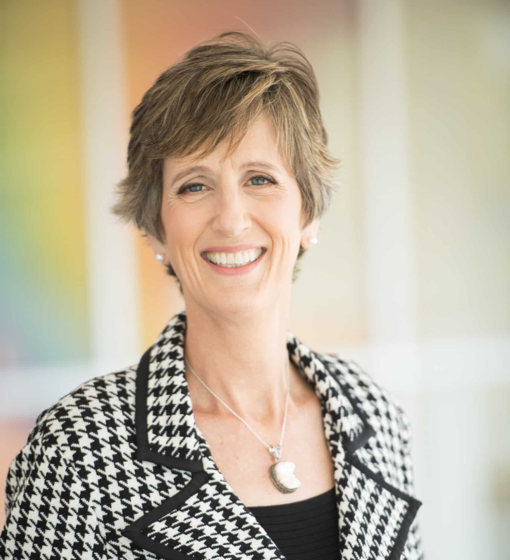 Smiling woman in houndstooth blazer.