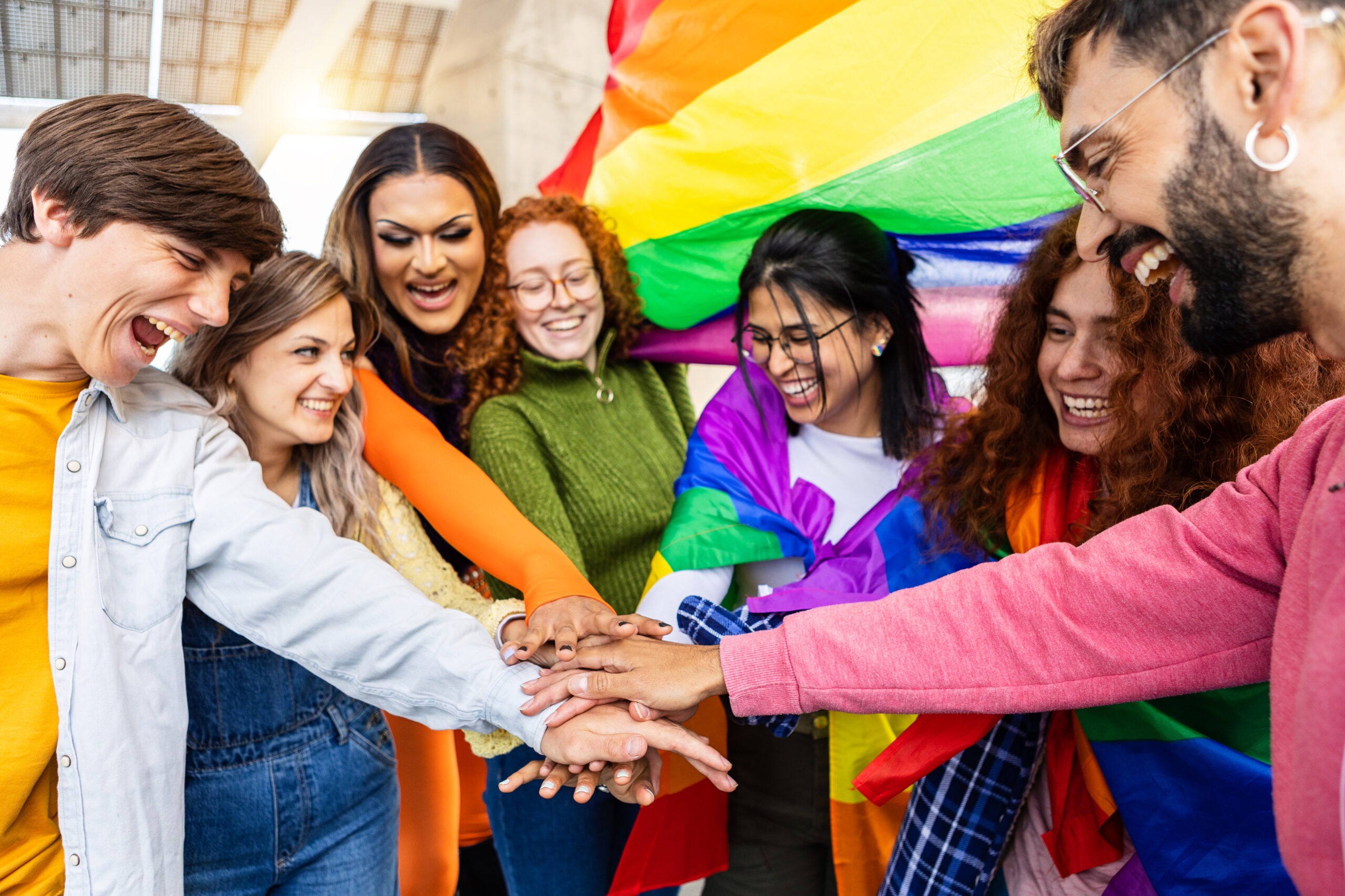 homosexual diverse group of young people stacking hands together outdoors